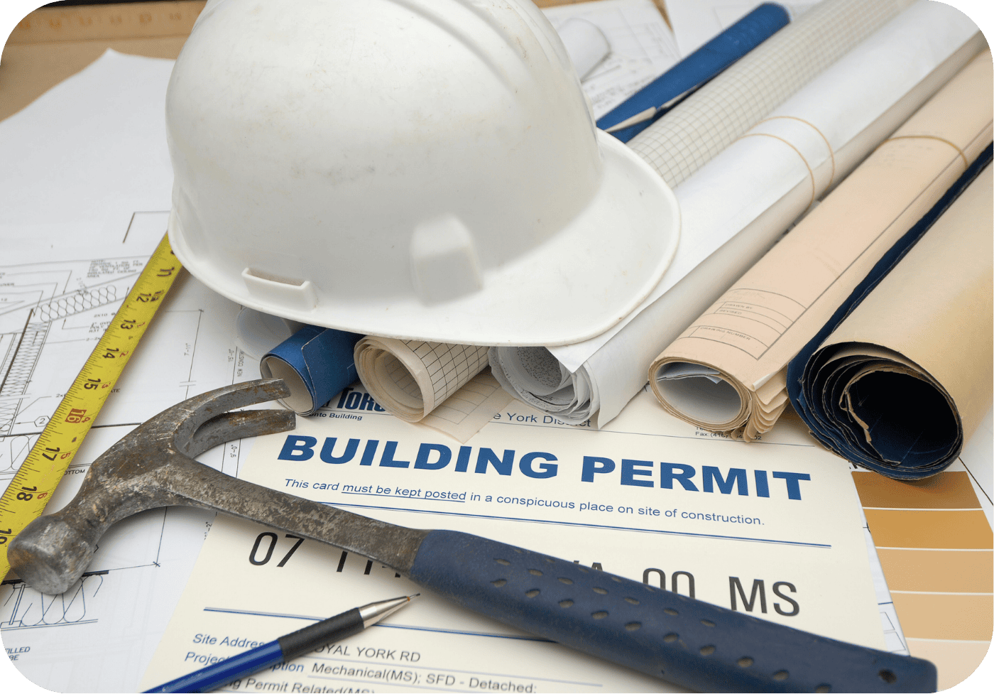 Close-up of building permit with hard hat, hammer, and rolled site plans—symbolizing Greater Houston Land & Permit Services’ hands-on approach to permitting and construction readiness.